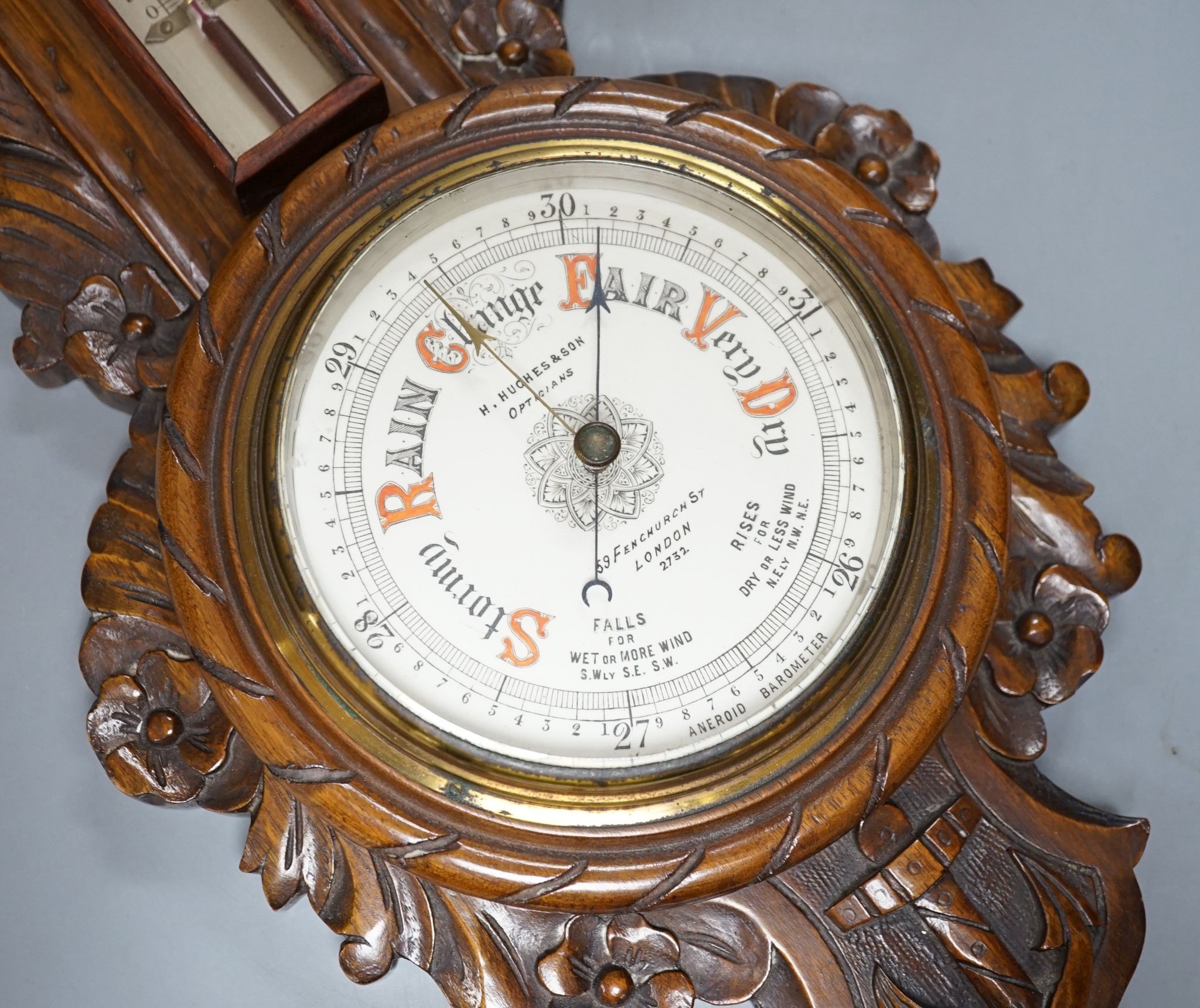 A Victorian carved walnut aneroid barometer with timepiece